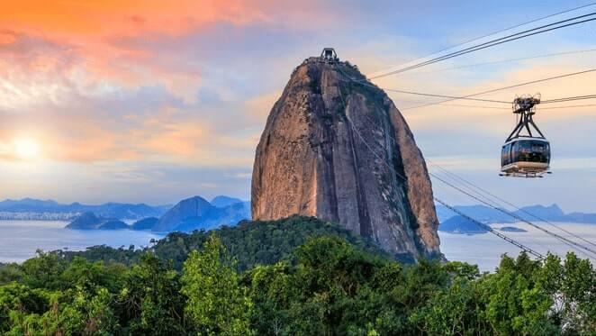 Vista do Pão de Açucar em um pôr do sol com um bondinho se aproximando